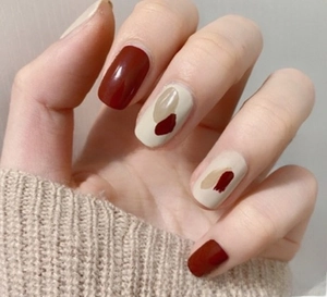 Detailed view of dark red and beige nail stickers with abstract hand-painted art