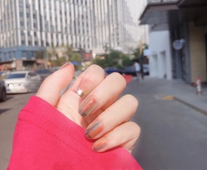 Macro shot of stylish watercolor gradient nail stickers in coral, grey, and caramel hues