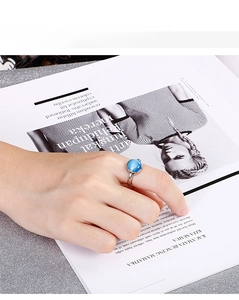 Detail of a silver steel ring with a blue cat eye stone on a model's finger