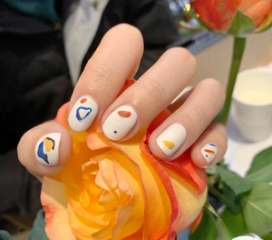 Macro shot of matte off-white nail stickers featuring abstract colorful art patterns