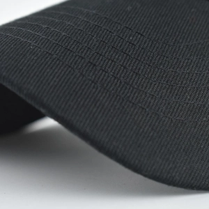 Macro shot of durable twill fabric and reinforced stitching on a black baseball cap brim