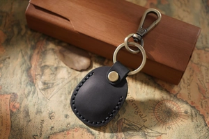 Detail of hand-stitched black leather Airtag keychain case with antique bronze metal ring