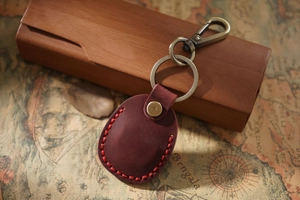 Close-up of retro reddish-brown leather keychain with red stitching and bronze hardware
