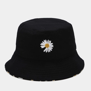 Close-up of white daisy embroidery and cotton fabric texture on a black bucket hat