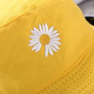 Close-up of a yellow bucket hat featuring detailed white daisy floral embroidery on cotton