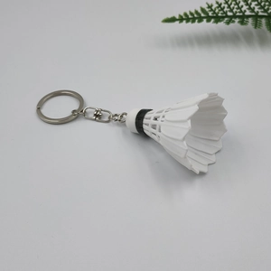 Detail shot of a white shuttlecock keychain with metal ring on a minimalist background