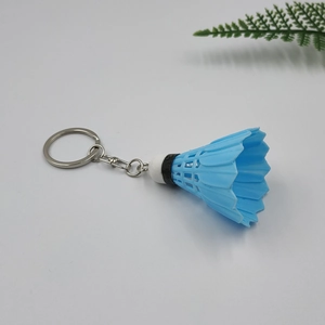 Close-up of a realistic blue badminton shuttlecock keychain with metal link on white background