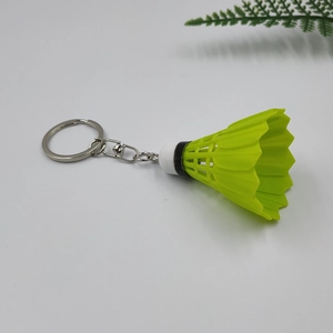 Macro shot of a neon green badminton shuttlecock keychain on a white background