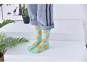 Detail of mint green cotton socks with orange smiley flower patterns worn by model