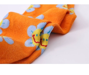 Macro shot of orange cotton sock featuring blue and yellow smiley flower knit patterns