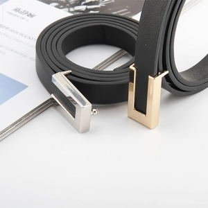 Detailed view of narrow black leather belts with polished gold and silver metal buckles