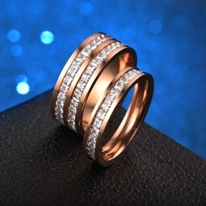 Close-up of rose gold titanium couple rings with two rows of white square zircon stones