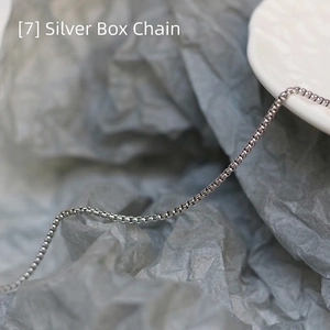 Macro detail of silver square box chain necklace displayed on minimalist background
