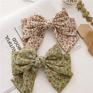 Close-up of elegant oversized triple-layered floral bow hair clips in beige and green fabric