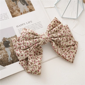 Detail of oversized bow hair clip with floral leopard print and ribbed fabric texture