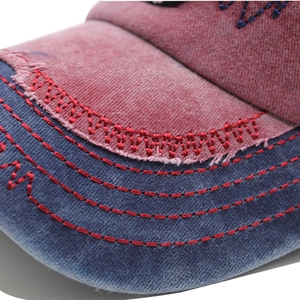 Close-up of distressed baseball cap with embroidery, contrast stitching and frayed edges