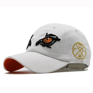 Detail of white cotton baseball cap showing fine eye embroidery and gold badge detail