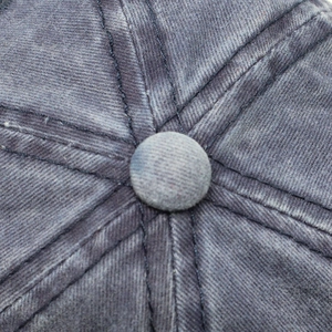 Macro view of washed cotton baseball cap top showing distressed fabric and stitching