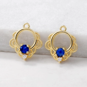 Detailed macro of gold filigree cloud pendants with blue and clear zircon stones