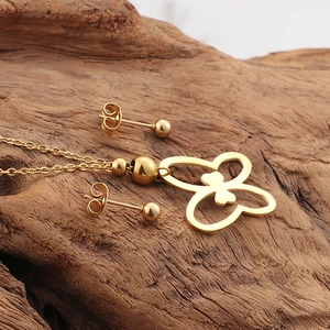 Minimalist 18K gold butterfly necklace and stud earrings set on a natural wood surface