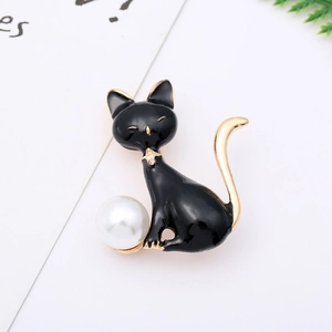 Close-up of black enamel cat brooch with gold star detail and a large white pearl bead