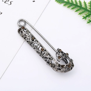 Close-up of vintage hollow silver brooch with dark rhinestones and filigree design