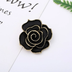 Detailed view of a black and gold rose brooch on a decorative aesthetic card