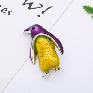 Close-up of cute purple and yellow enamel penguin brooch on white display card