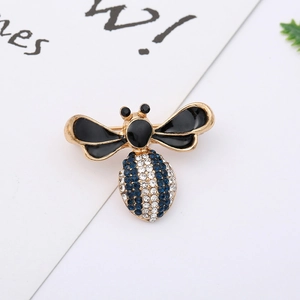 Close-up of a bee brooch with gold finish, blue rhinestones, and black enamel wings