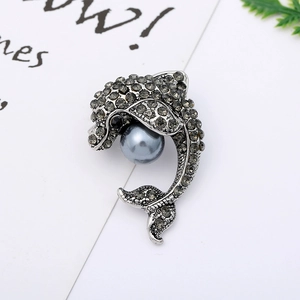Detail of silver dolphin brooch featuring grey rhinestones and a large round imitation pearl
