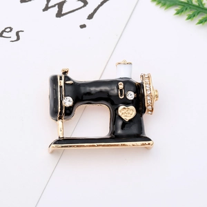 Detailed macro view of a vintage sewing machine brooch with black enamel and gold crown