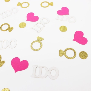 Macro detail of I DO letters, pink hearts and gold glitter rings wedding confetti