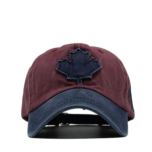 Close-up of a vintage burgundy baseball cap with a blue maple leaf patch and distressed edges