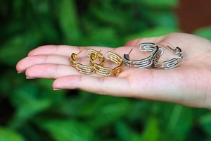 Sparkling pave-set zircon paperclip earrings in gold and silver held by a model