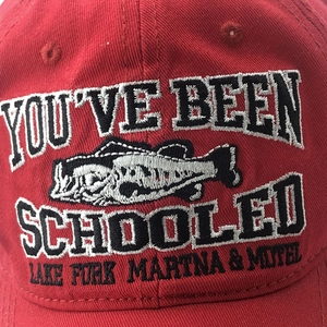 Primo piano dei dettagli del ricamo su un berretto da baseball in cotone rosso con logo pesce