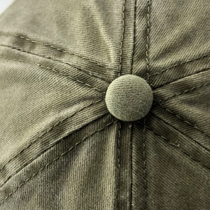 Macro shot of olive green washed cotton baseball cap crown with reinforced stitching