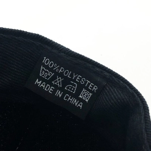 Macro shot of 100% polyester care label and washing instructions on a black baseball cap