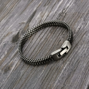 Macro shot of stainless steel dragon bone chain with vintage buckle on gray wood