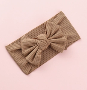 Detailed texture of brown ribbed knit baby headband with a large decorative bow