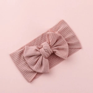 Pink ribbed knit baby headband featuring a soft elastic large bow on a matching background
