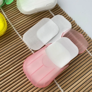 Detail of portable pink soap paper case with white sheets on a bamboo mat background