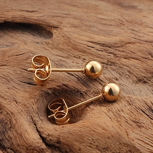 Minimalist 18K gold-plated ball stud earrings set displayed on a natural wood surface