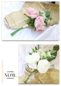 Detailed view of pink and ivory silk peonies with green leaves and vintage newspaper decor