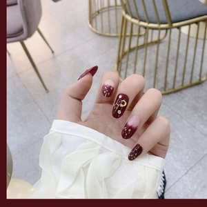 Deep burgundy press-on nails with star and moon charms and gold foil gradient finish