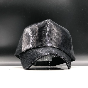 Detail view of a black sequined baseball cap with adjustable strap on a display stand