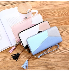 Detailed view of color-block long wallets with tassel charms and wrist straps on desk
