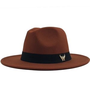 Detail of a brown wool fedora hat featuring a gold eagle badge on a black ribbon band