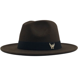 Detail of dark brown fedora wool hat featuring a black ribbon and gold eagle badge