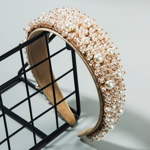 Close-up of wide leather headband with dense white pearls and gold bead embellishments