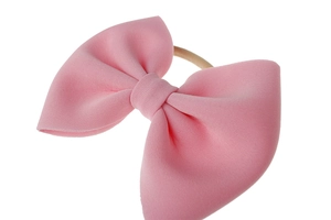 Vue détaillée d'un bandeau pour bébé rose avec un grand nœud en maille douce